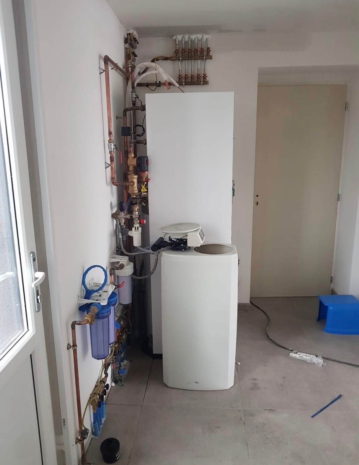 Local technique équipé d’un ballon d’eau chaude, d’un adoucisseur et d’une filtration installés par L.I.J Chauffage à Monchecourt.