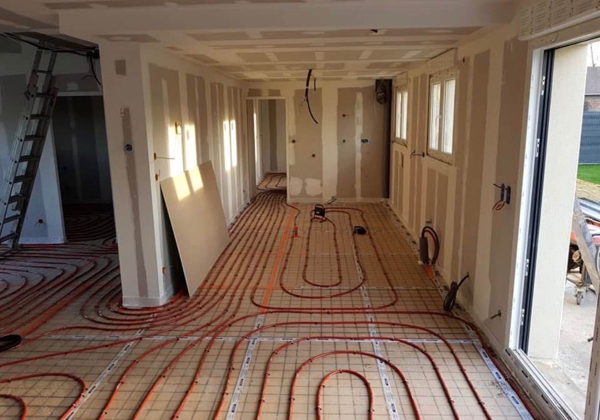 Plancher chauffant en cours de pose, boucles rouges apparentes, chantier de construction neuve suivi par L.I.J Chauffage près de Monchecourt.
